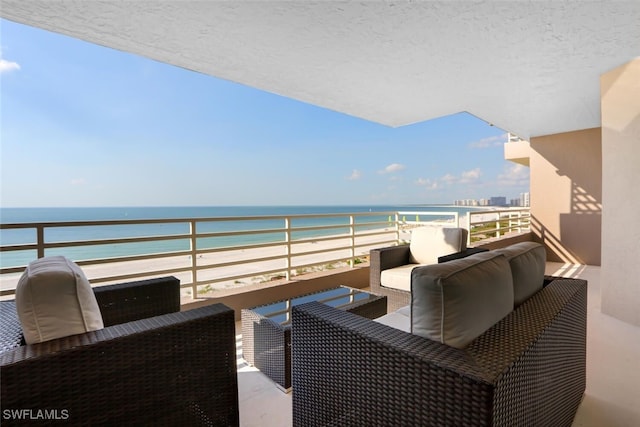 balcony with an outdoor hangout area, a water view, and a beach view