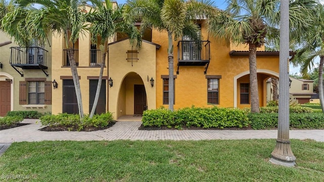 view of front of home featuring a balcony and a front yard