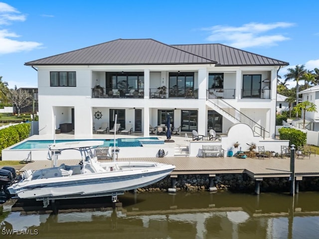 back of house with a water view, a patio, a balcony, and stucco siding