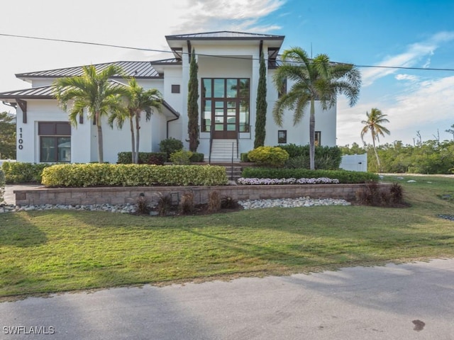 view of front of house with metal roof, a front lawn, a standing seam roof, and stucco siding