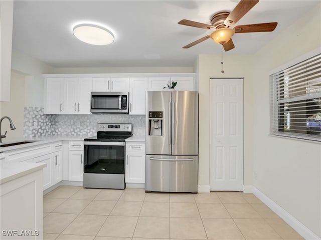 kitchen featuring decorative backsplash, stainless steel appliances, sink, light tile patterned floors, and white cabinets