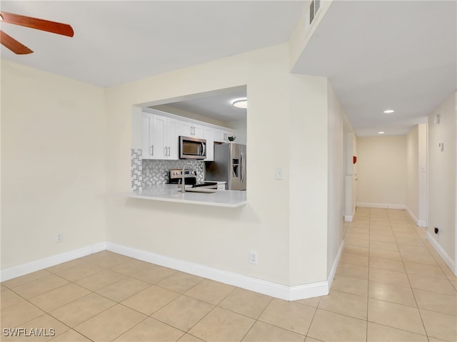 kitchen featuring ceiling fan, light tile patterned flooring, decorative backsplash, white cabinets, and appliances with stainless steel finishes