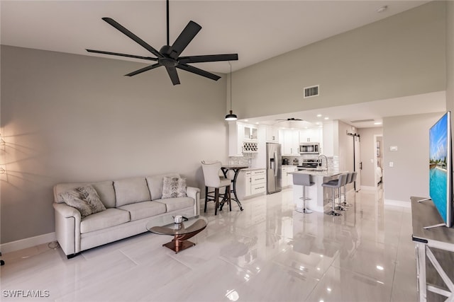 living room featuring ceiling fan, sink, and high vaulted ceiling