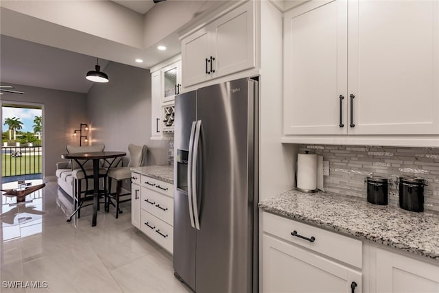 kitchen featuring tasteful backsplash, stainless steel fridge with ice dispenser, light stone counters, pendant lighting, and white cabinets