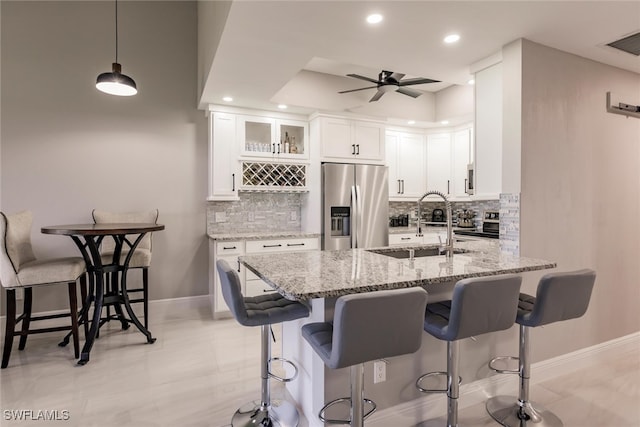 kitchen with light stone countertops, pendant lighting, decorative backsplash, white cabinets, and appliances with stainless steel finishes