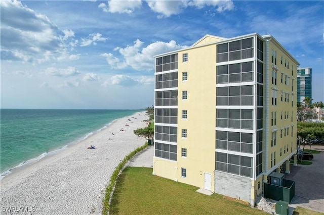 view of building exterior with a water view and a view of the beach