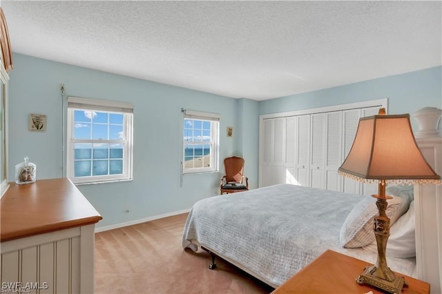 bedroom featuring light carpet, a textured ceiling, and a closet