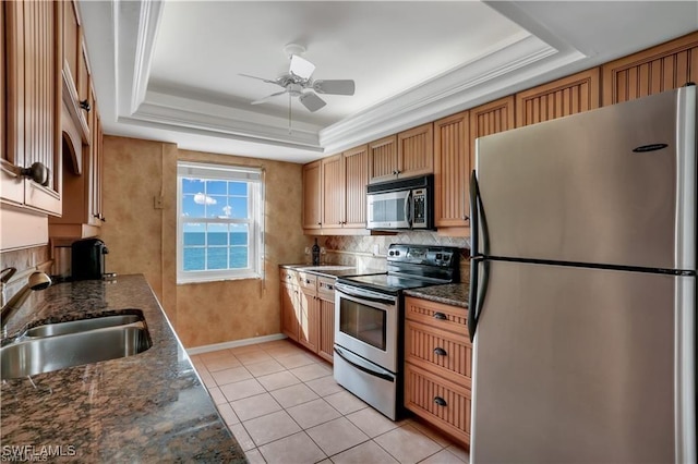 kitchen with stainless steel appliances, tasteful backsplash, a tray ceiling, and sink