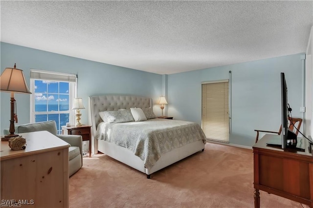 bedroom featuring light carpet, a textured ceiling, and a water view