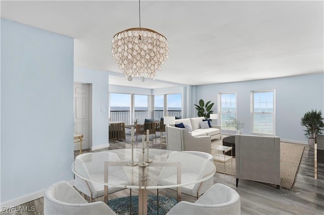 dining area with a chandelier, wood-type flooring, and a water view