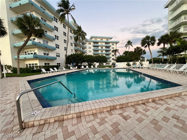 pool at dusk featuring a patio