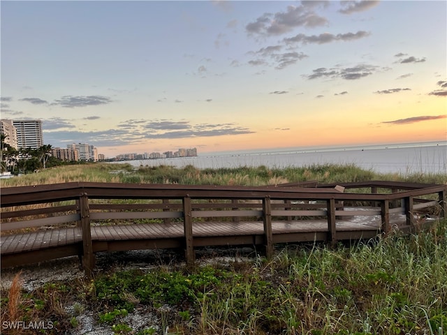 deck at dusk featuring a water view