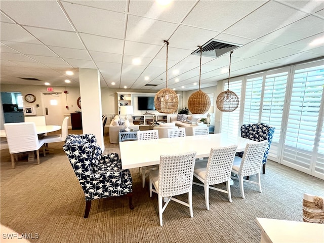 carpeted dining area featuring a drop ceiling