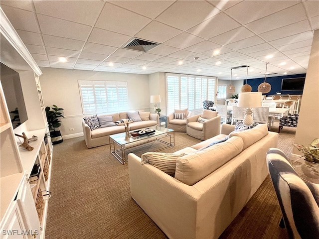 living room featuring carpet and a drop ceiling