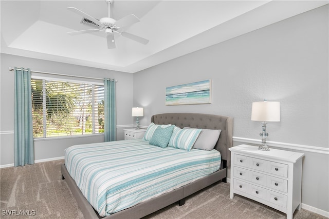 bedroom featuring light colored carpet, a raised ceiling, and ceiling fan