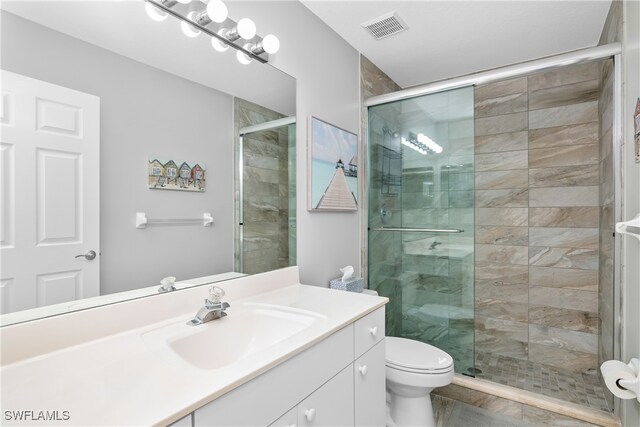 bathroom featuring vanity, a shower with shower door, and toilet