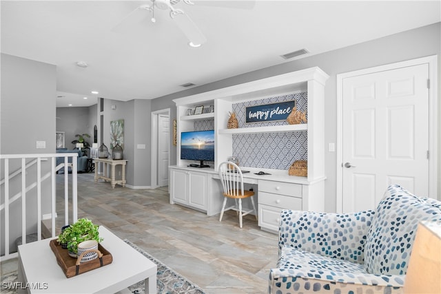 living room with ceiling fan and built in desk