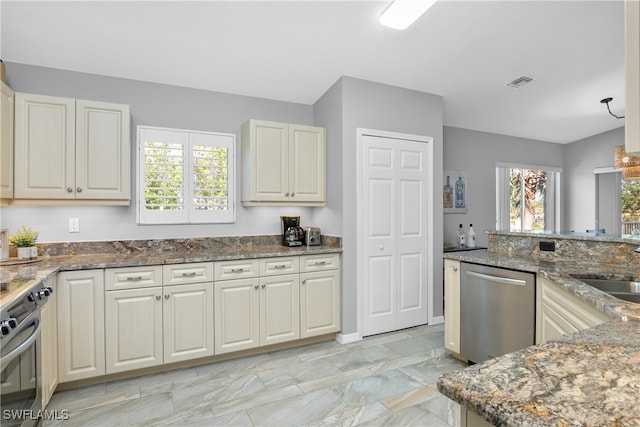 kitchen with appliances with stainless steel finishes, dark stone counters, and sink