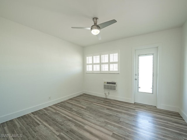 spare room with wood-type flooring, an AC wall unit, and a wealth of natural light