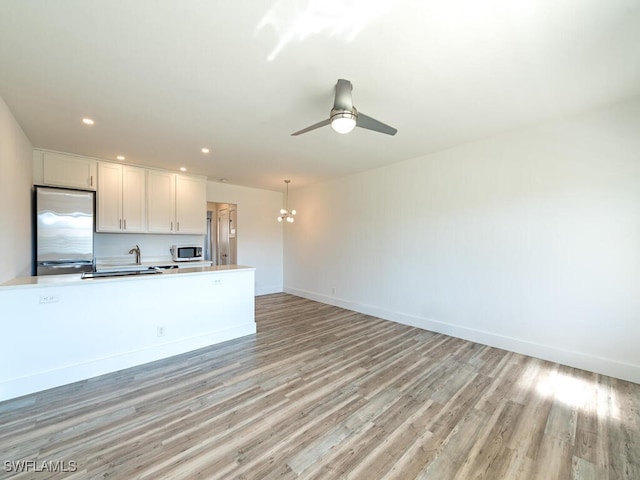 kitchen with a chandelier, light hardwood / wood-style flooring, white cabinetry, and stainless steel refrigerator