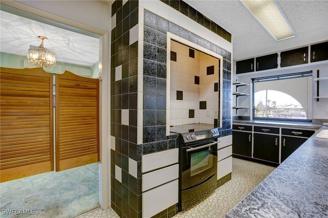 kitchen featuring pendant lighting, electric range, light tile patterned floors, a textured ceiling, and a notable chandelier