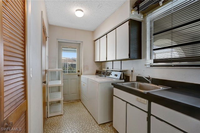 laundry room with cabinets, washing machine and dryer, sink, and a textured ceiling