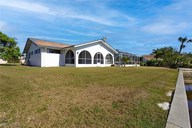 rear view of property with a yard and a lanai