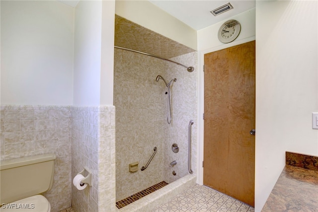 bathroom featuring a tile shower, tile walls, and toilet