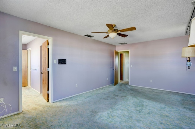 spare room with a textured ceiling, light colored carpet, and ceiling fan