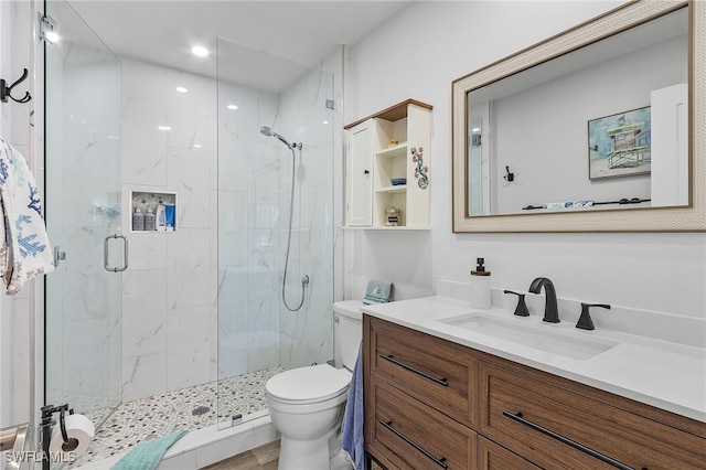 bathroom featuring vanity, toilet, and a shower with door