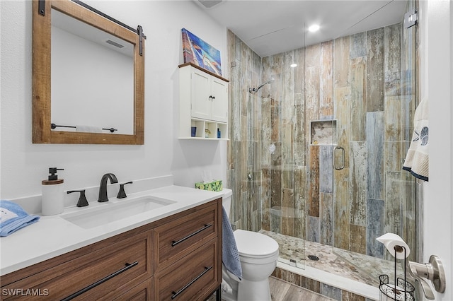 bathroom with toilet, vanity, a shower with door, and hardwood / wood-style flooring