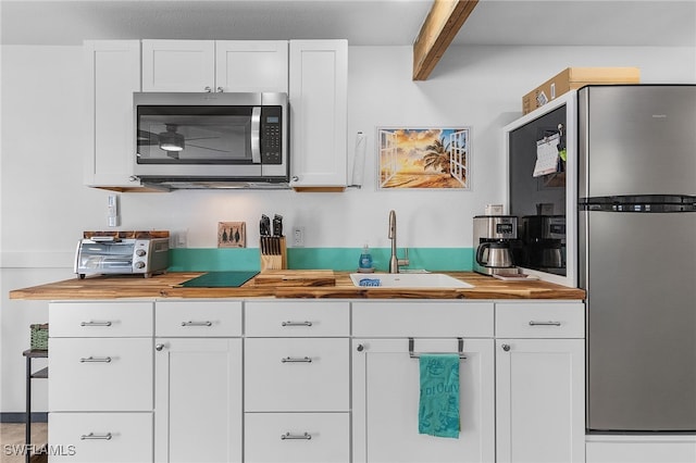 kitchen featuring appliances with stainless steel finishes, butcher block countertops, white cabinetry, and sink