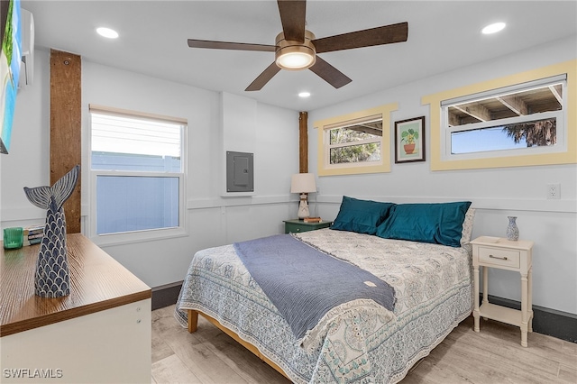 bedroom with electric panel, light hardwood / wood-style floors, and ceiling fan