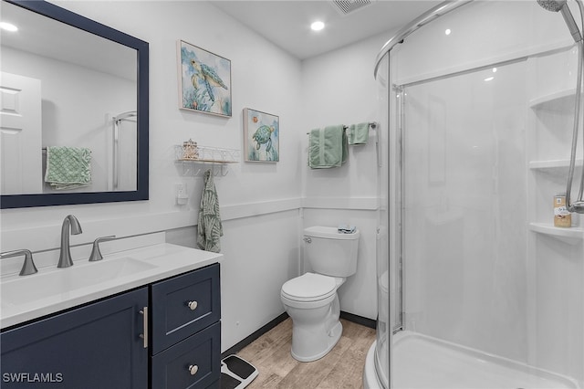 bathroom with hardwood / wood-style flooring, vanity, toilet, and a shower with shower door