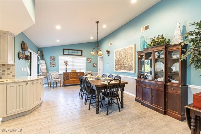 dining room with light wood-type flooring and vaulted ceiling