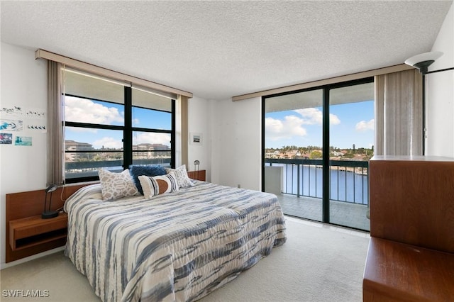 bedroom with multiple windows, a water view, access to exterior, and floor to ceiling windows