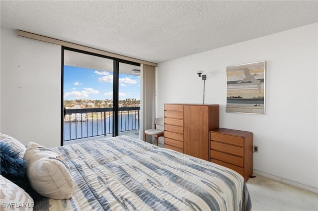 bedroom with carpet, floor to ceiling windows, access to outside, a water view, and a textured ceiling