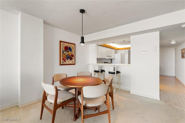 dining room with light carpet and a textured ceiling