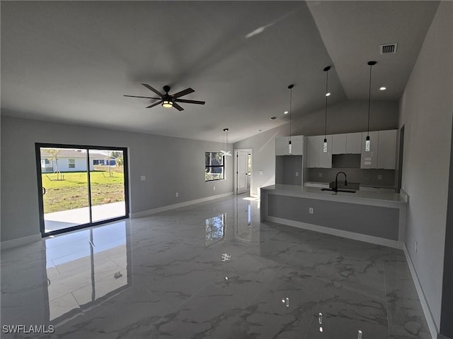 interior space featuring white cabinetry, sink, ceiling fan, pendant lighting, and vaulted ceiling