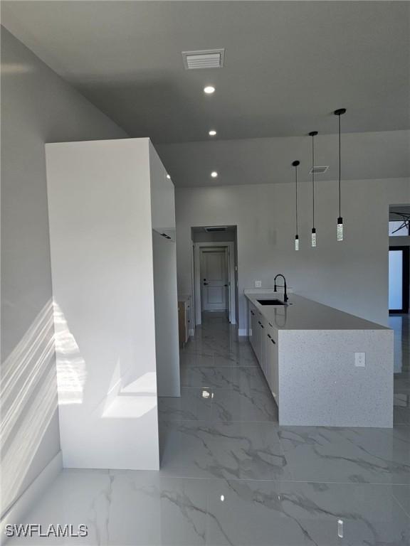 kitchen with white cabinets, decorative light fixtures, and sink