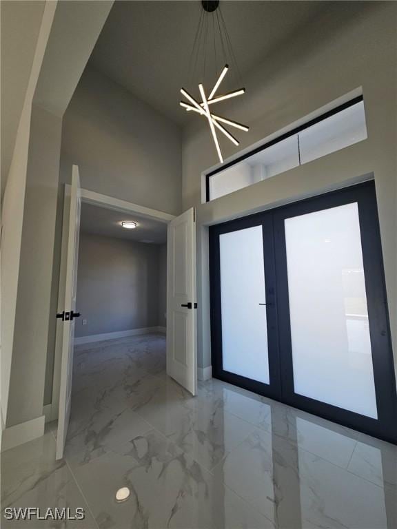 interior space with an inviting chandelier, a high ceiling, and french doors