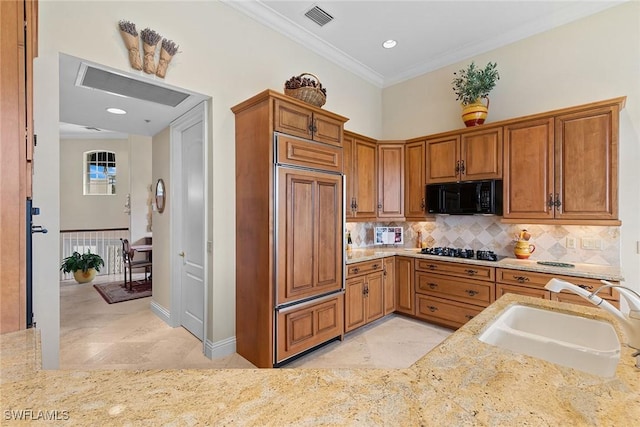 kitchen featuring light stone countertops, sink, stainless steel gas cooktop, paneled built in fridge, and ornamental molding