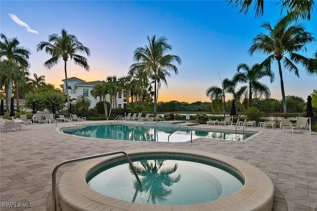 pool at dusk featuring a community hot tub and a patio area