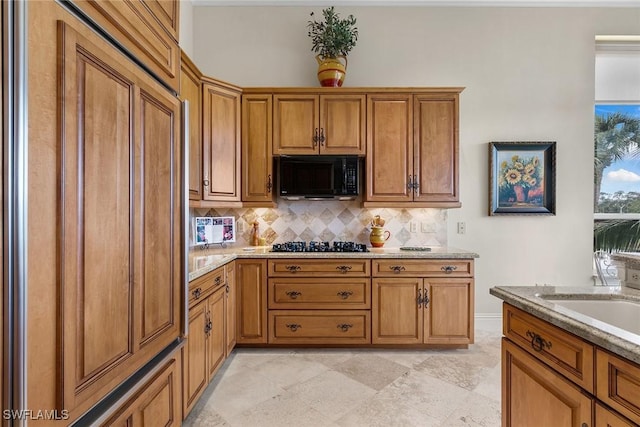 kitchen with gas cooktop, tasteful backsplash, light stone countertops, and sink