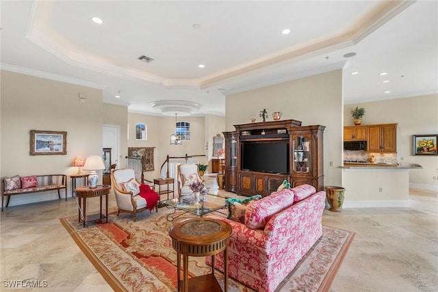 living room with a tray ceiling and ornamental molding