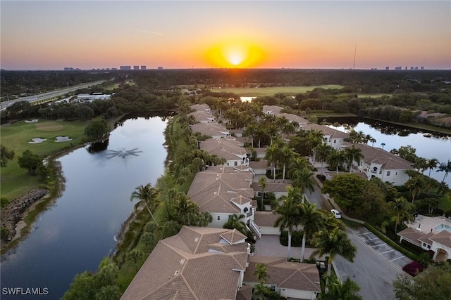 aerial view at dusk featuring a water view