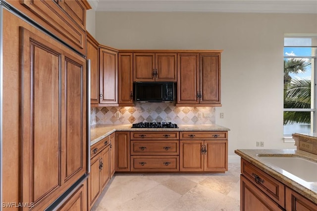 kitchen with a sink, backsplash, black appliances, and brown cabinetry