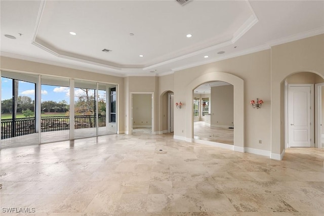 unfurnished room featuring a tray ceiling, arched walkways, and a healthy amount of sunlight