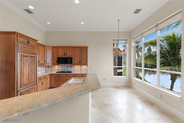 kitchen with paneled fridge, visible vents, a sink, black microwave, and tasteful backsplash