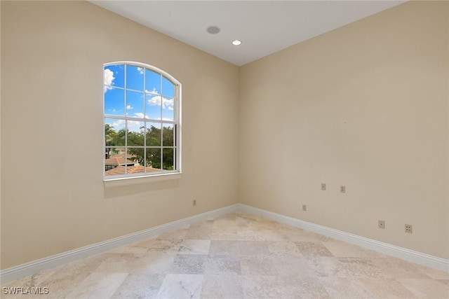 spare room with recessed lighting and baseboards